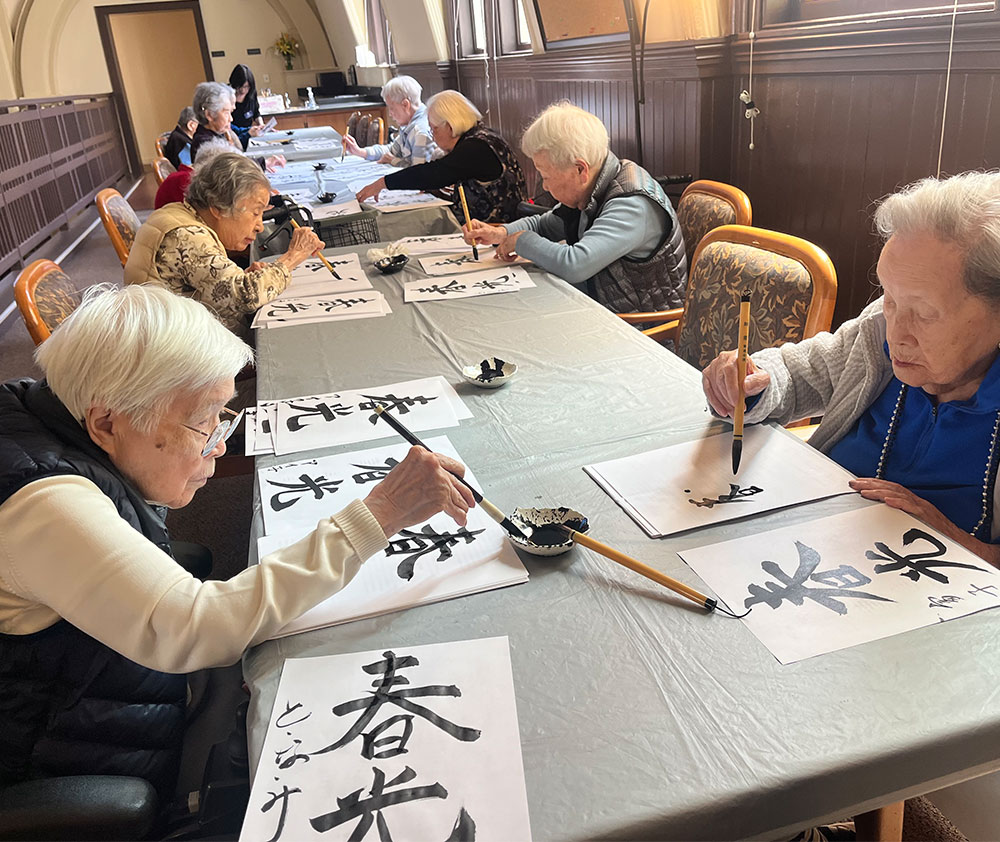 Residents practicing Japanese calligraphy during a cultural activity at Kokoro Assisted Living